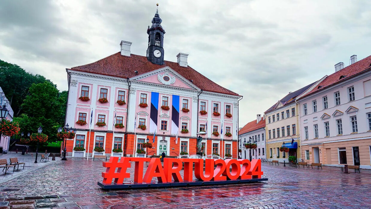 Vista de la plaza central de Tartu, Estonia, con edificios históricos del siglo XVIII y el Ayuntamiento al fondo.